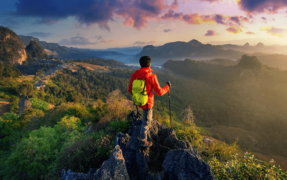 Hiker standing on mountain summit at sunset