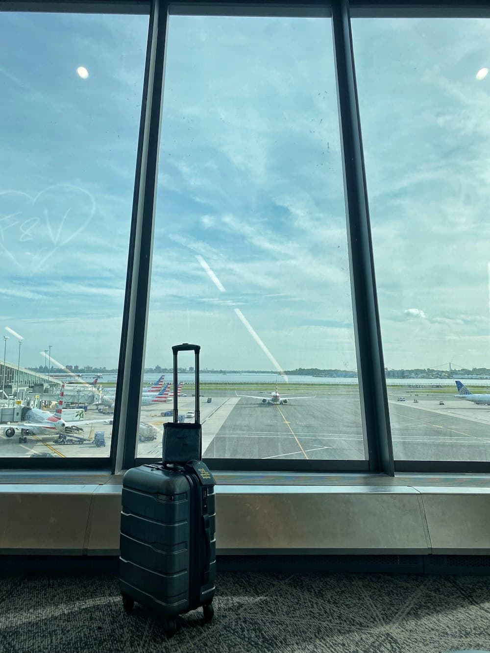 Luggage at airport terminal overlooking airplanes at sunset