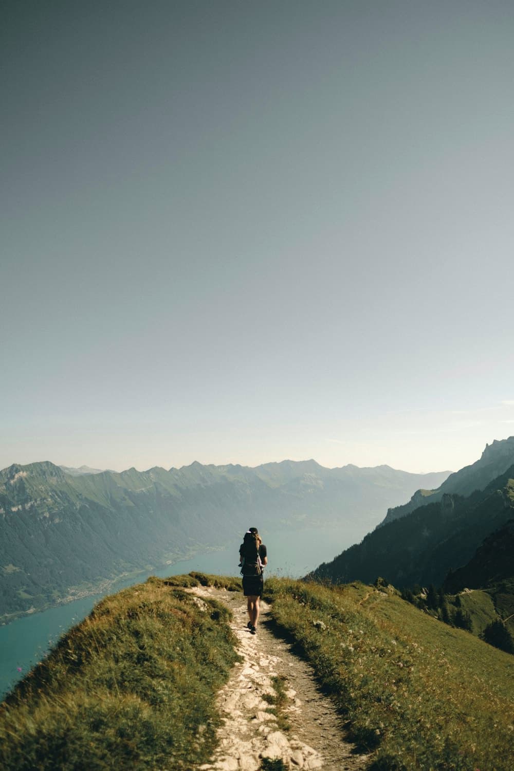 Hiker on mountain summit overlooking scenic landscape at sunset